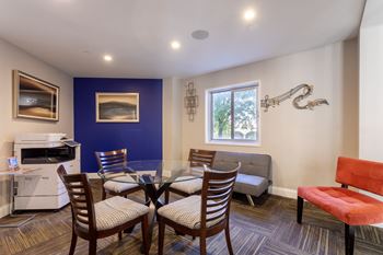 A living room with a dining room table and chairs and a kitchen with a microwave